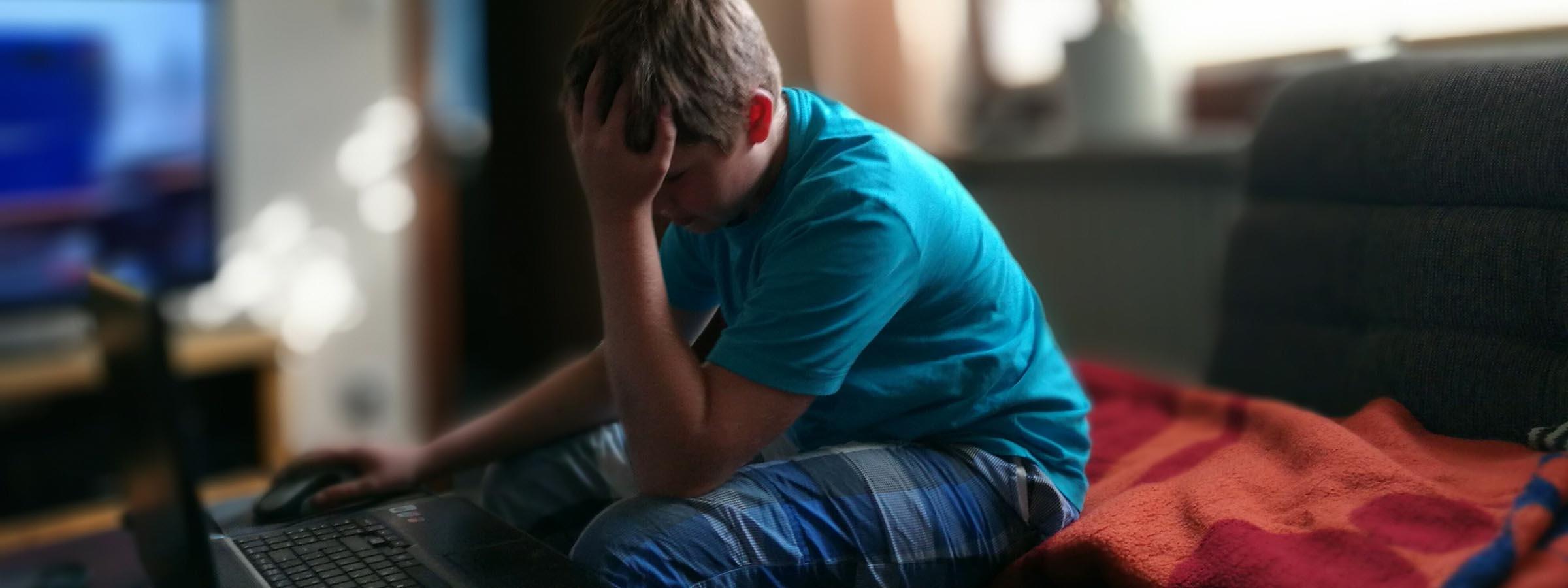 Boy sitting with head in his hands.