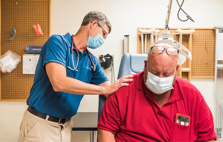 Doctor using a stethoscope on a man's back to check his breathing