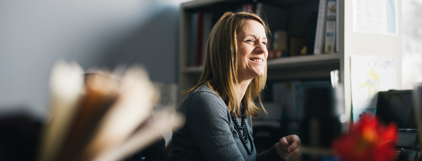 A woman looking over smiling while working on billing workflows