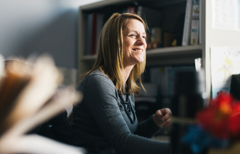 A woman looking over smiling while working on billing workflows