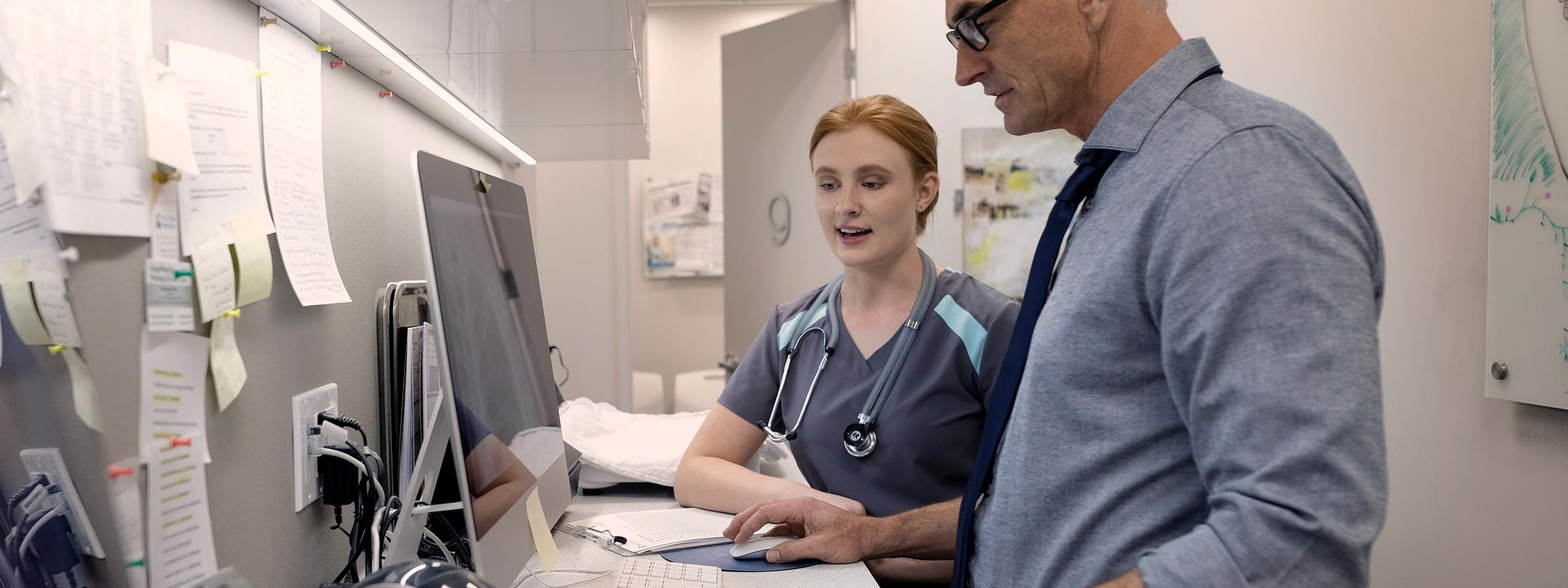 Physician and advanced practice provider talking in front of a computer