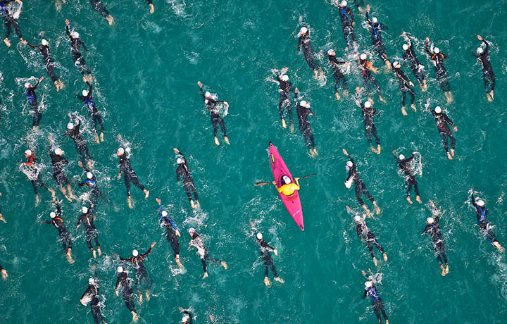 Image of a lone kayaker amid a sea of swimmers
