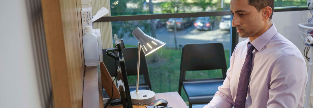 Clinician sitting at a desk working on a computer to coordinate care between clinics and ASCs.