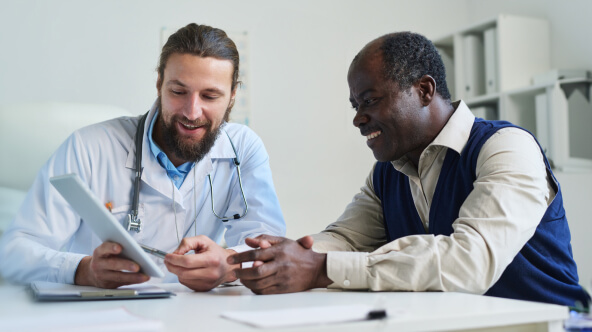 male physician reviewing electronic health record with medicare patient