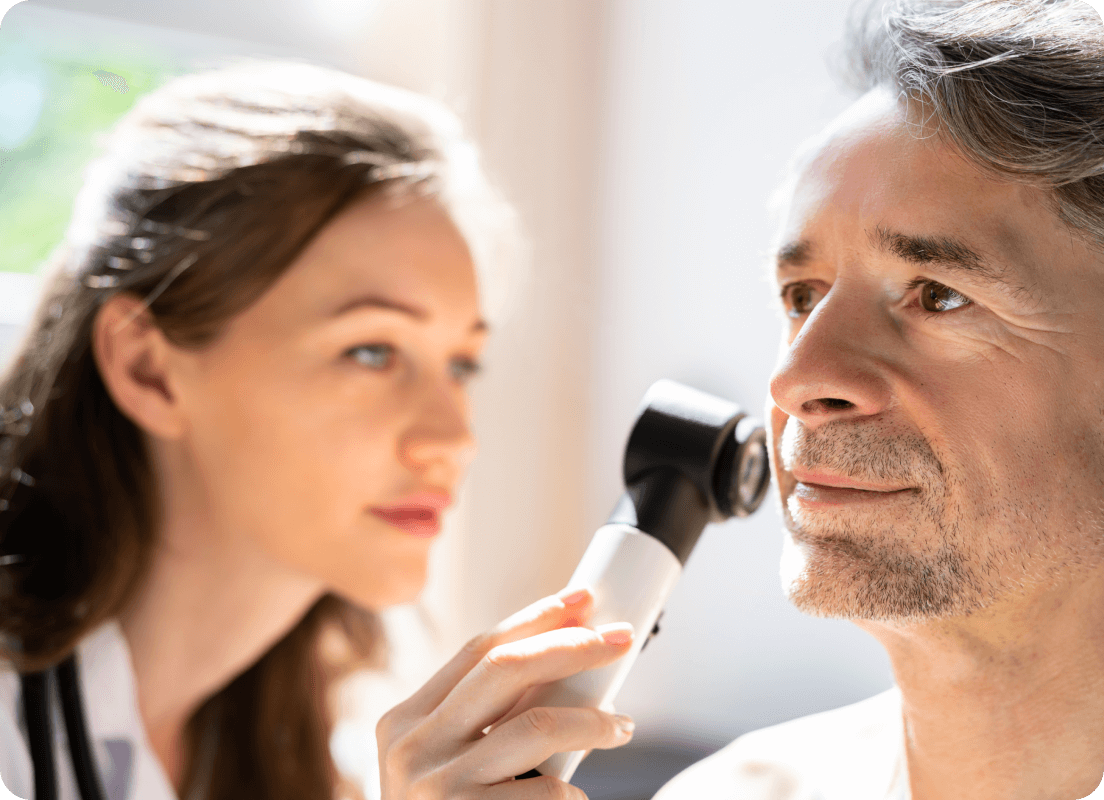 dermatologist examining a mans face using medical equipment