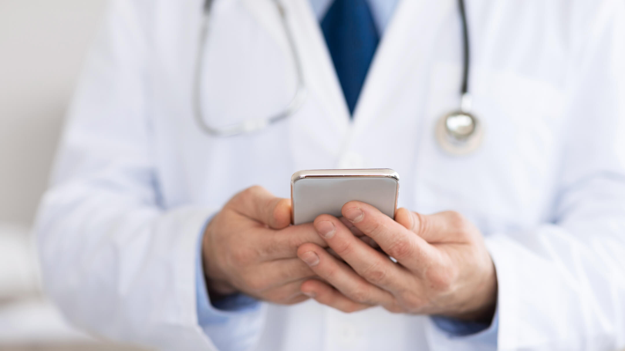 physician in white coat using apps on mobile 