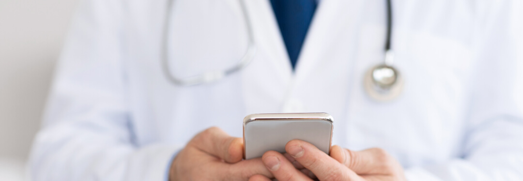 physician in white coat using apps on mobile
