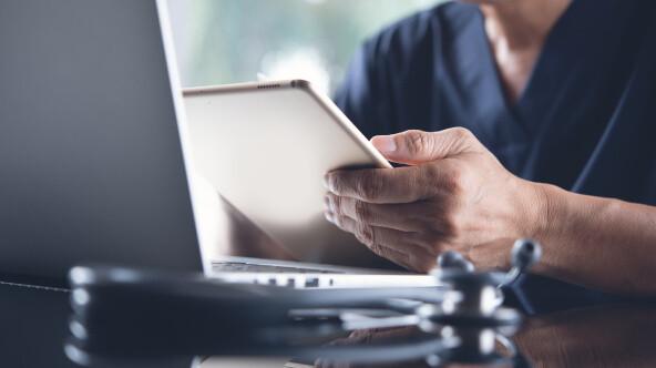 Physician looking at his iPad and reviewing AI clinical documentation.