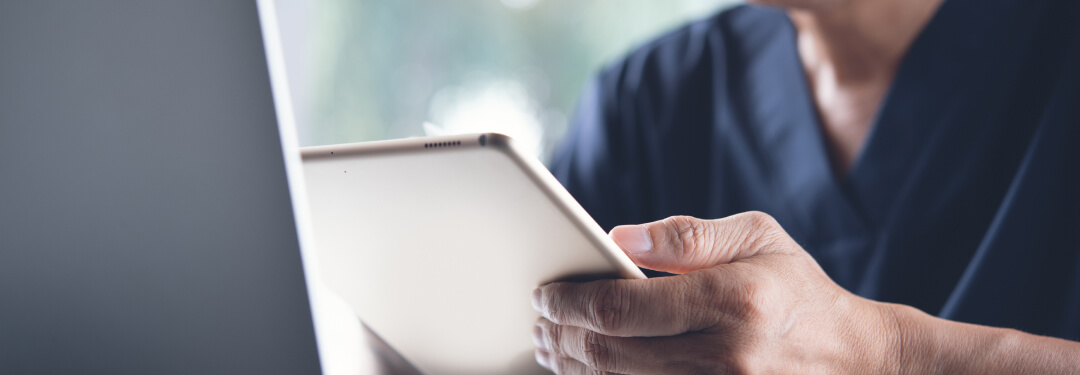 Physician looking at his iPad and reviewing AI clinical documentation.