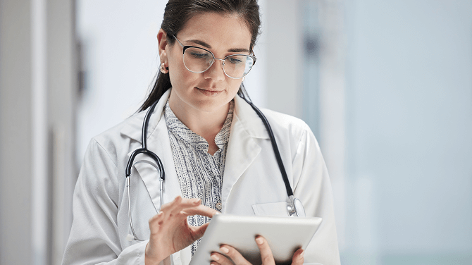 A physician interacts with a tablet, showcasing AI's assistance in managing administrative duties.