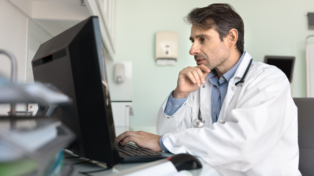 Physician sitting at desk in front of monitor