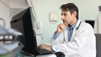 Physician sitting at desk in front of monitor