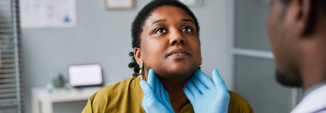 Physician wearing gloves checking female patients throat.