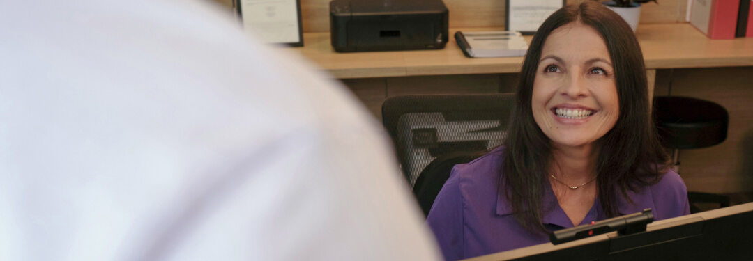 The receptionist greets a patient and prepares to confirm their insurance information via AI OCR.