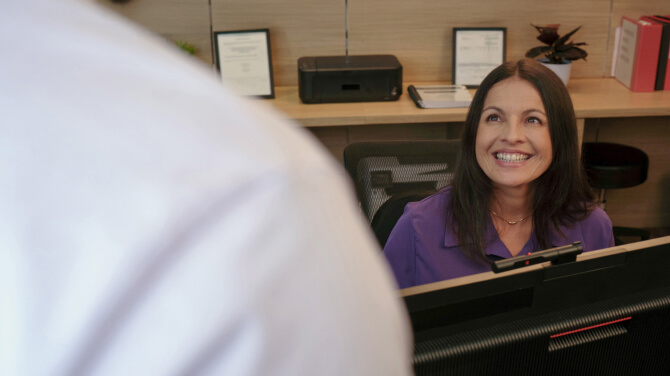 The receptionist greets a patient and prepares to confirm their insurance information via AI OCR.