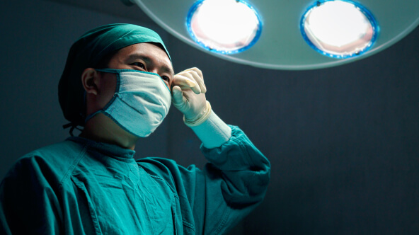 A surgeon wearing a surgical mask, looks focused and prepared for a medical procedure.