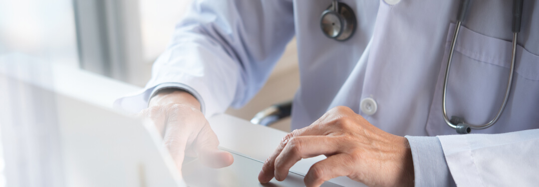 A physician typing on a laptop, highlighting the connection of global software to local healthcare through Agentic AI technology.