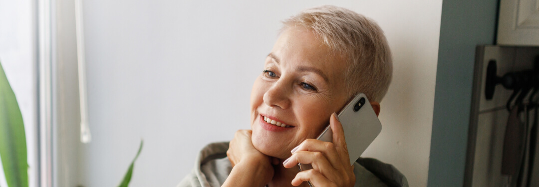 A patient smiles while scheduling an appointment over the phone with athenahealth's Marketplace partner's Generative Voice AI.