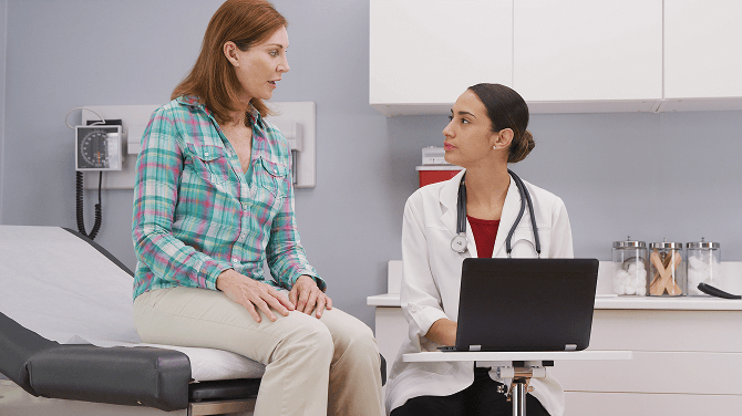 A patient consults with a doctor in a hospital room, discussing her care in an ambulatory setting.