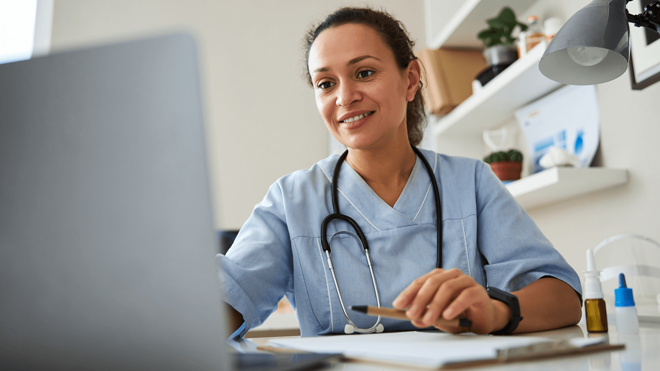 A physician works at a desk with a laptop, exploring EHR selection pitfalls for her practice.