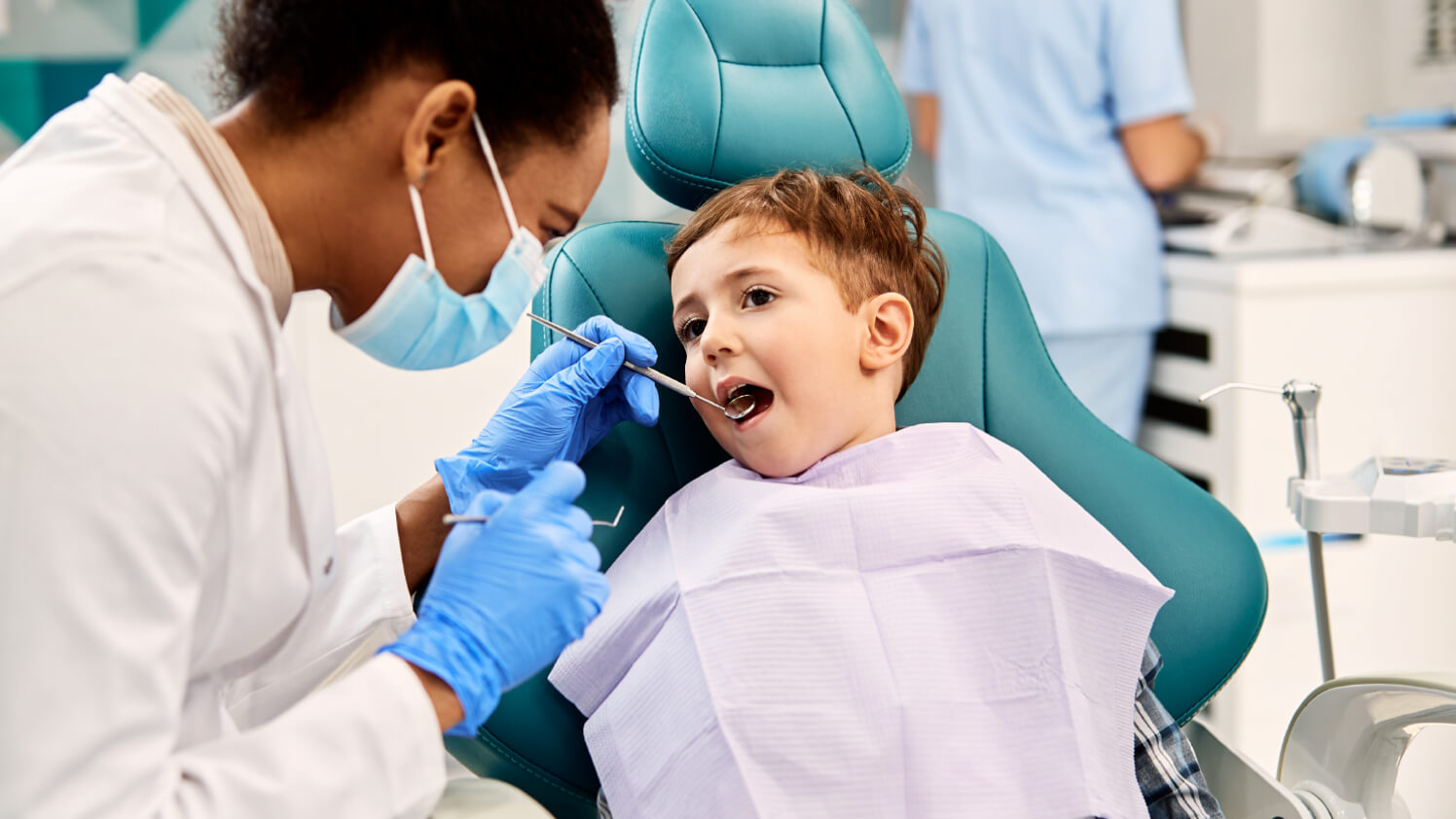 A dental provider examines a young patients mouth during an oral exam.