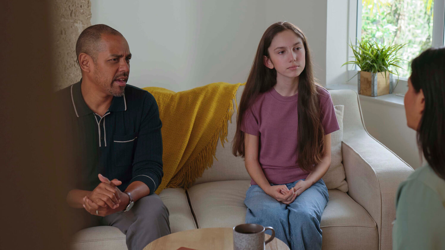 A young patient and their guardian chat with a mental health doctor in their office.