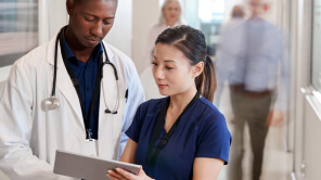 A doctor and a nurse examine a tablet together, sharing insights on patient care in a healthcare facility.