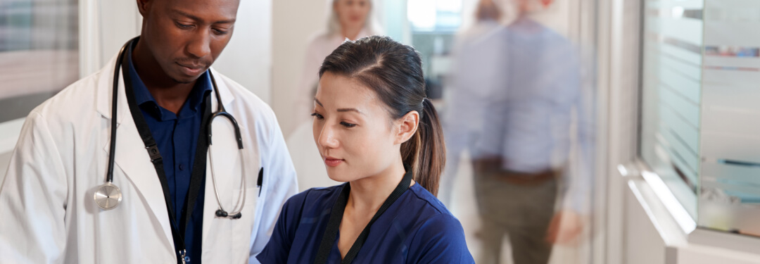 A doctor and a nurse examine a tablet together, sharing insights on patient care in a healthcare facility.