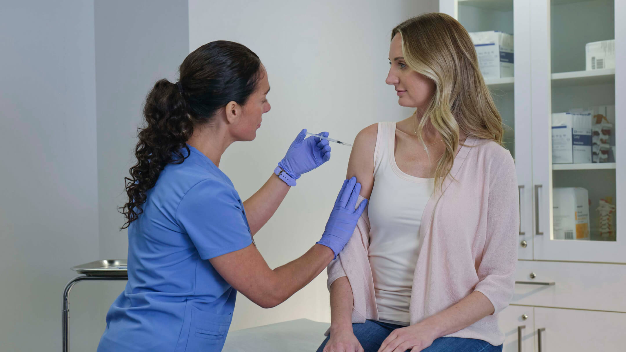 A patient is having her arm examined by a nurse, showcasing how ChartSync organizes vaccine records effectively.