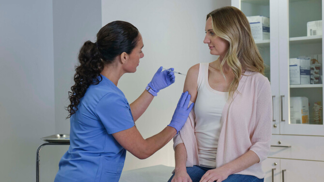 A patient is having her arm examined by a nurse, showcasing how ChartSync organizes vaccine records effectively.