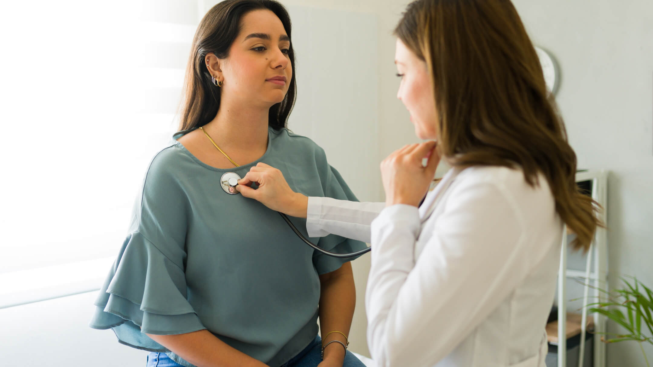A physician uses a stethoscope to monitor the heart rate of patient in a medical setting.