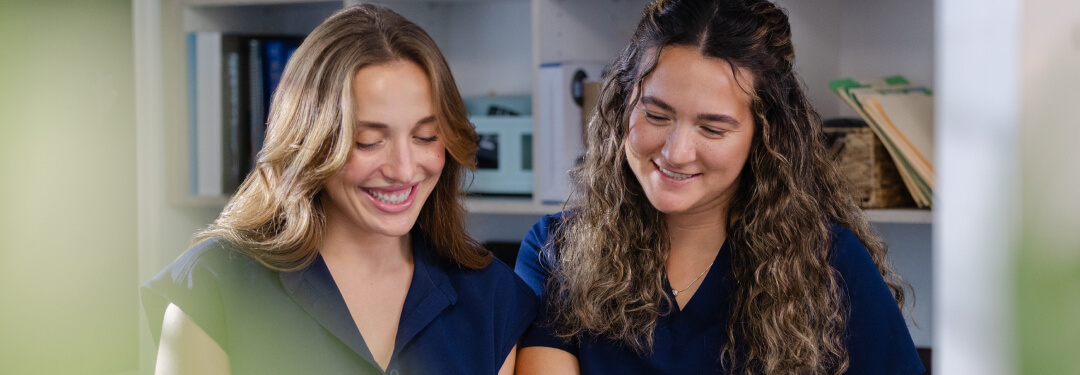 Two members of clinical staff smiling seeing care recommendations provided by predictive models in athenaOne.