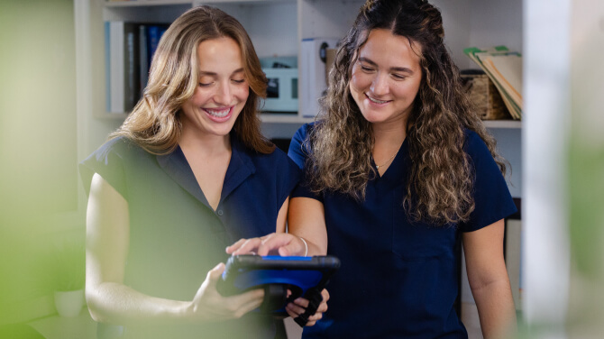 Two members of clinical staff smiling seeing care recommendations provided by predictive models in athenaOne.