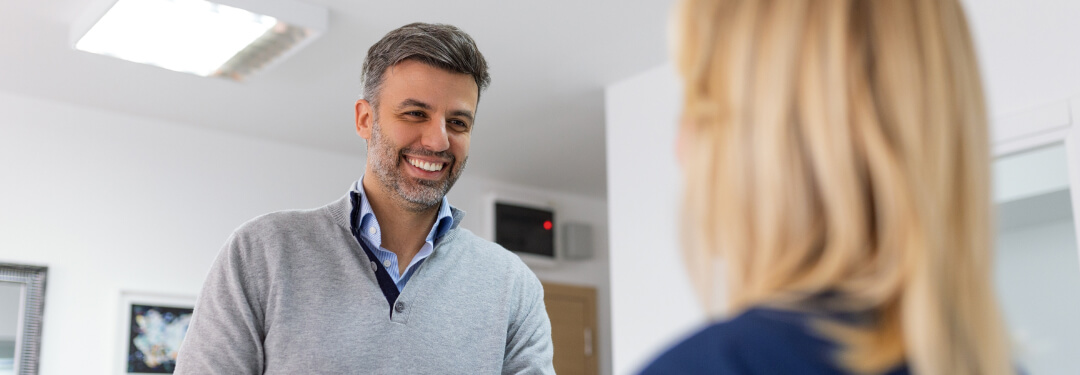 A patient and an admin discuss at a desk, highlighting the importance of direct payer integrations with EHR systems for practices.