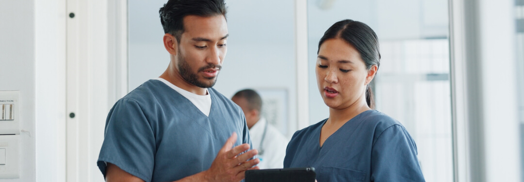 Two healthcare professionals review their new EHR on a tablet during onboarding training.
