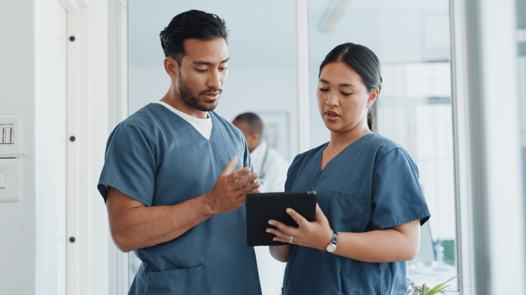 Two healthcare professionals review their new EHR on a tablet during onboarding training.