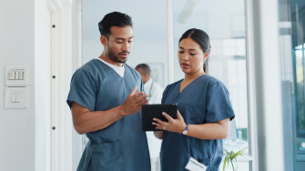 Two healthcare professionals review their new EHR on a tablet during onboarding training.