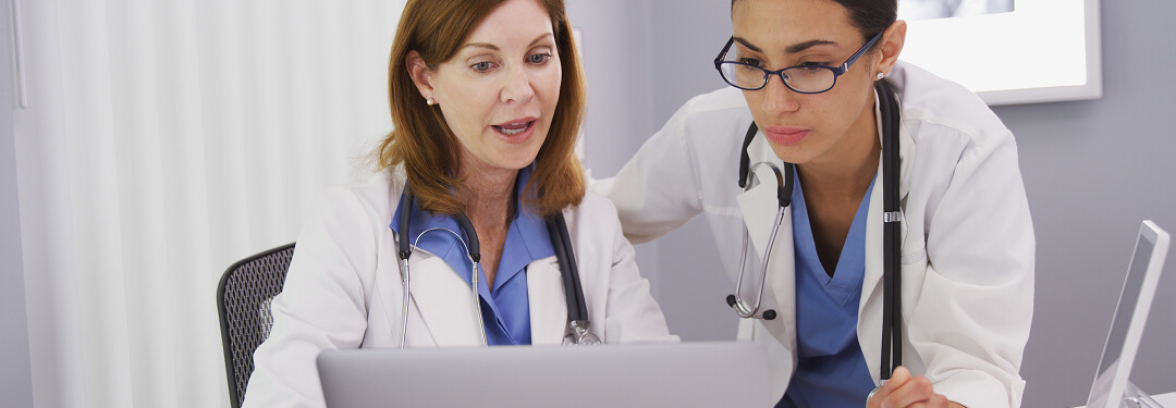 Two physicians collaborate over a laptop, discussing key features for future-proofing EHR selection.