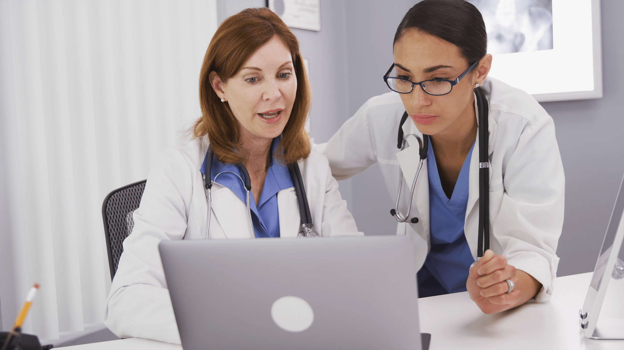 Two physicians collaborate over a laptop, discussing key features for future-proofing EHR selection.