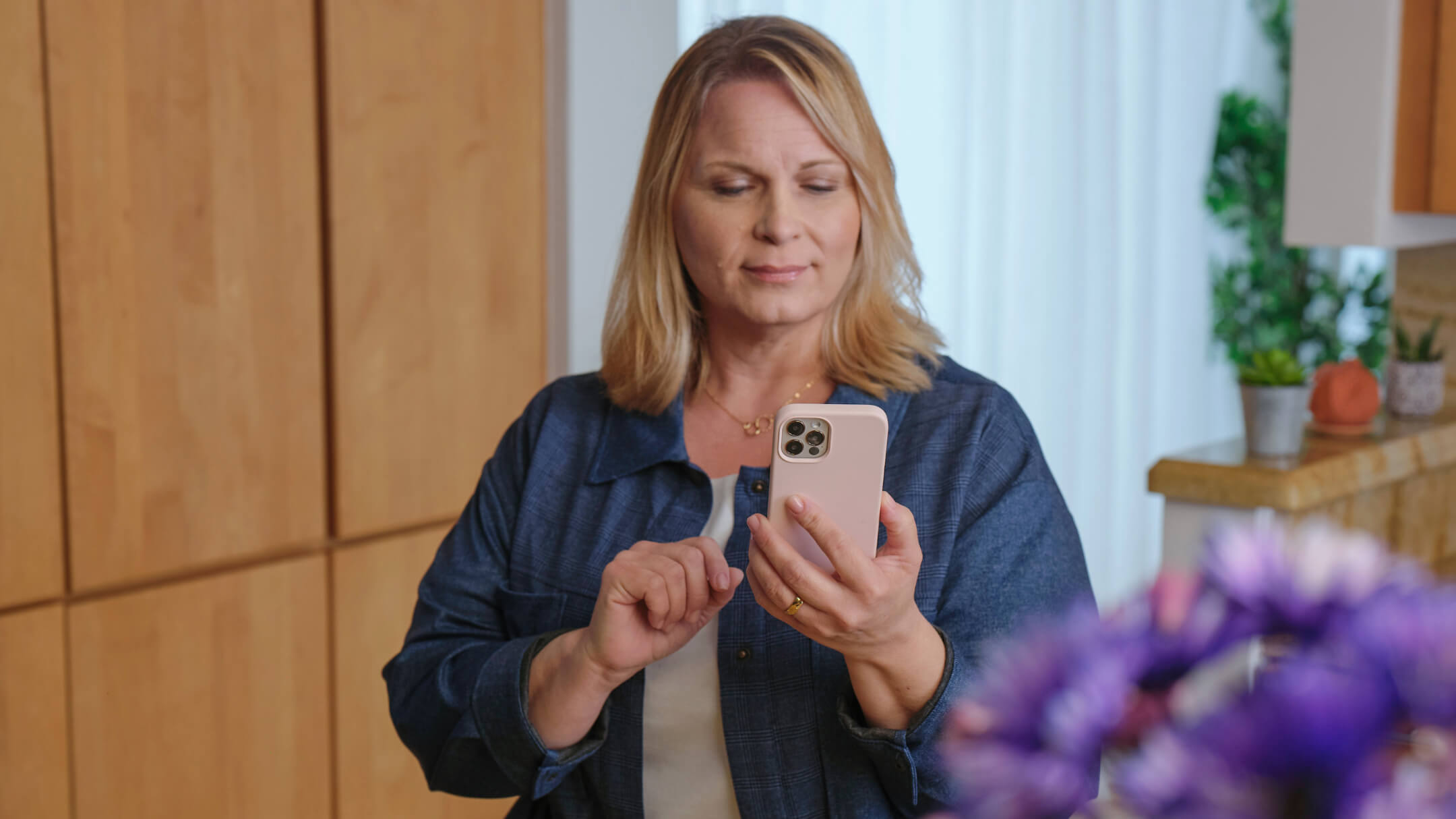 A woman looks at her smartphone using digital self check-in to enhance patient engagement.