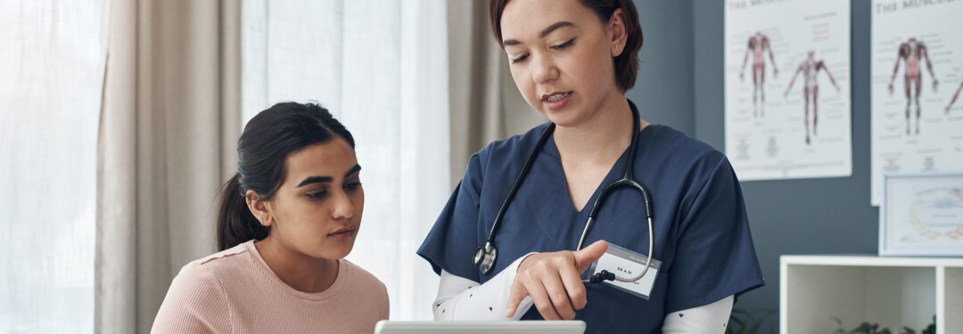  Nurse reviewing electronic health record with female patient during encounter
