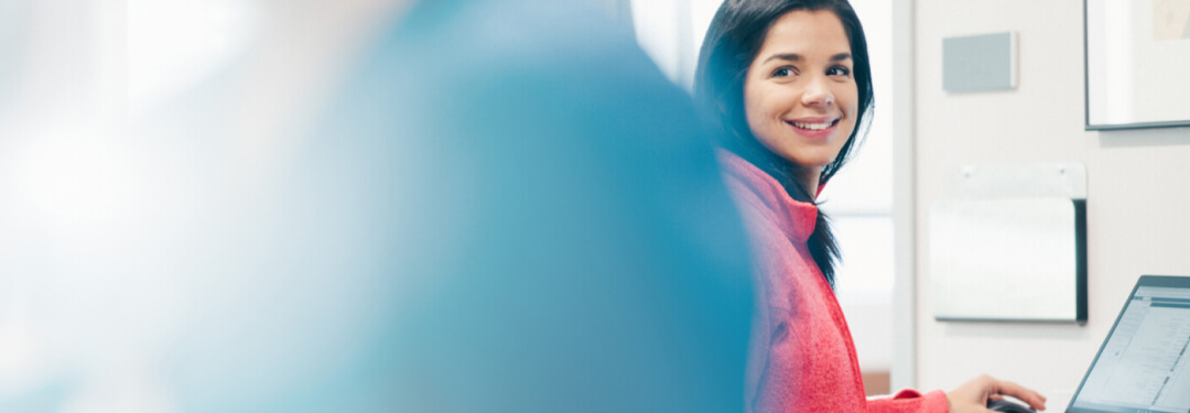 Receptionist at a medical practice smiling after helping a patient check in for their appointment.