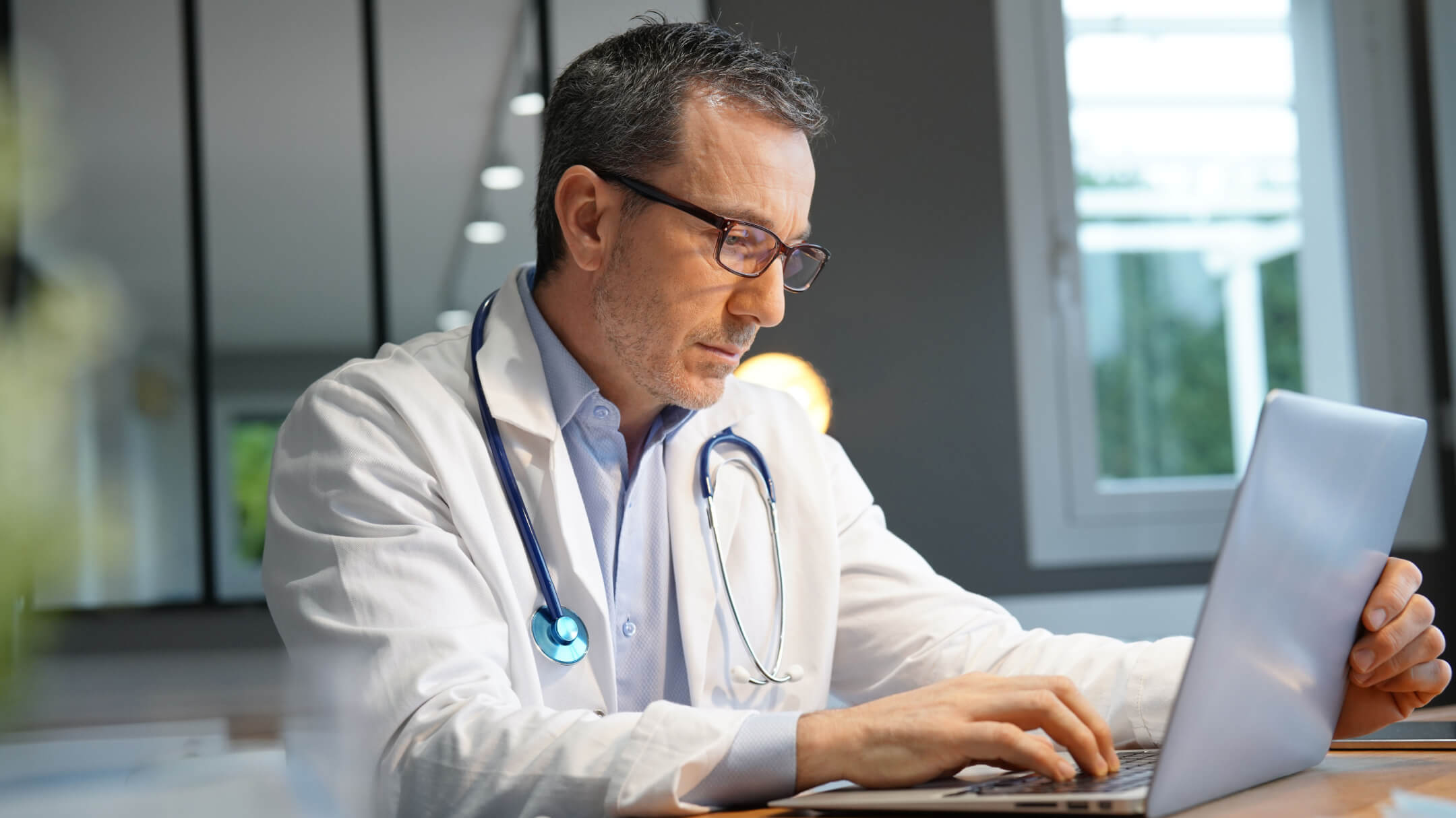 Doctor sits in concentration while working on a laptop