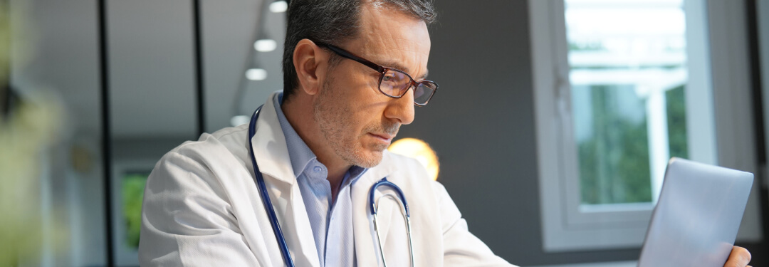 Doctor sits in concentration while working on a laptop