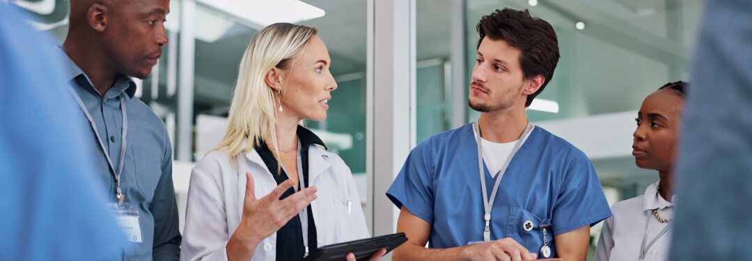 Physician speaking with medical staff holding a tablet