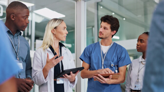 Physician speaking with medical staff holding a tablet