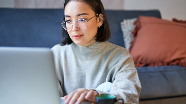 A patient sits at home, focusing on their laptop, securely accessing all of their health records in one spot.