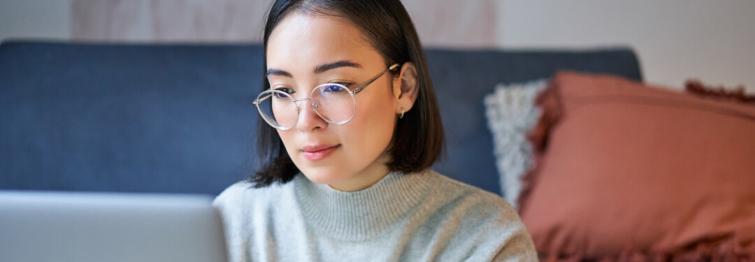 A patient sits at home, focusing on their laptop, securely accessing all of their health records in one spot.