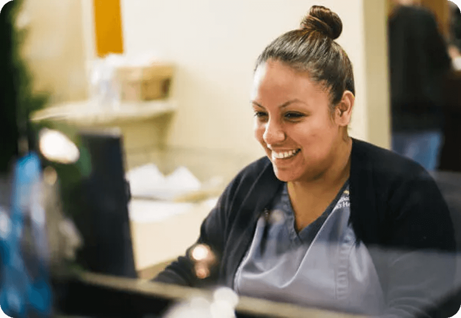 Staff smiling facing a laptop at her desk