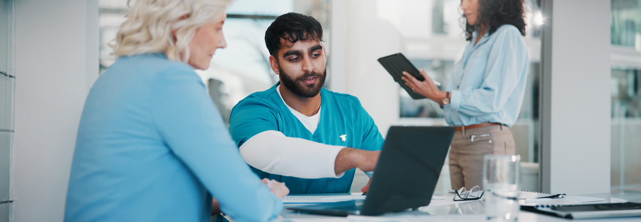 A physician sits at a table with two fellow physicians, discussing reimbursement challenges in healthcare today.